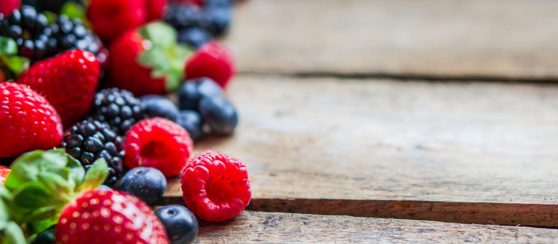 Mix of berries on rustic wooden background